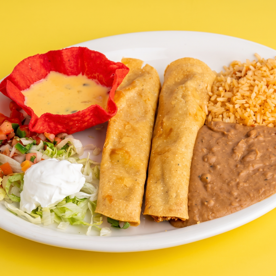 Mexican platter with two fried taquitos, rice, refried beans, pico de gallo, lettuce, sour cream, and queso in a red tortilla bowl.